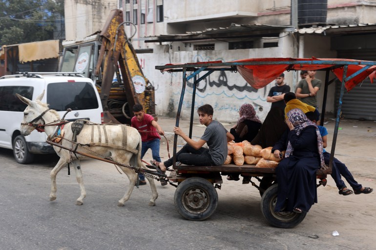 EDITORS NOTE: Graphic content / People transport bread as they ride a donkey-pulled cart in Gaza City on October 28, 2023. - Israeli air strikes destroyed hundreds of buildings in the Gaza Strip overnight, the civil defence service in the Hamas-controlled Palestinian territory said on October 28. (Photo by MOHAMMED ABED / AFP)