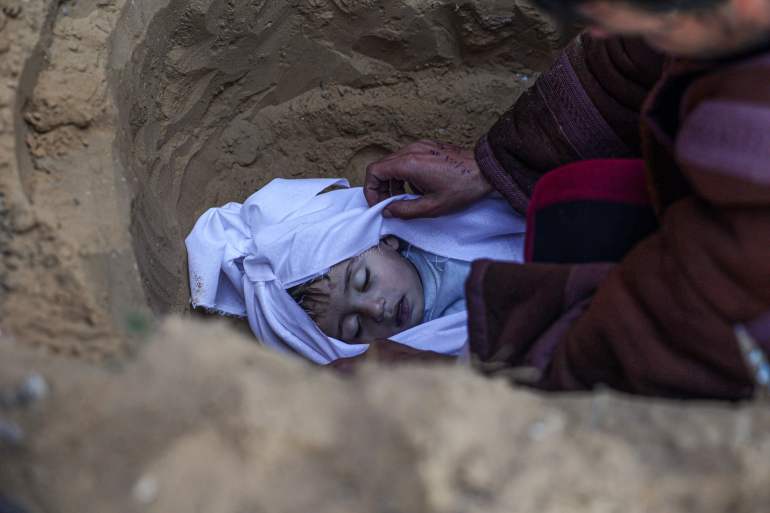 TOPSHOTS EDITORS NOTE: Graphic content / TOPSHOT - A man buries his child who was killed in overnight Israeli air strikes on the Moammar home, at a cemetery in east Khan Yunis in the southern Gaza Strip on February 26, 2024, amid ongoing battles between Israel and the militant Hamas movement. (Photo by SAID KHATIB / AFP) DATE 26/02/2024 SIZE x Country PSE SOURCE AFP/SAID KHATIB