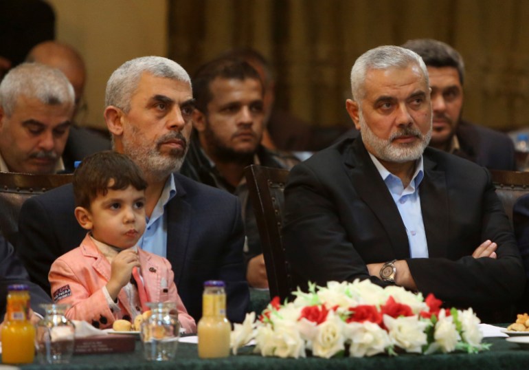 Yehiya Sinwar, left, a top Hamas official in Gaza, holding his son Ibrahim, sits near Ismail Haniyeh, right, a former top Hamas official in Gaza, as they listen to Khaled Mashaal, the outgoing Hamas leader in exile, during his news conference in Doha, Qatar, at Commodore hotel in Gaza City, Monday, May 1, 2017. The Islamic militant Hamas on Monday unveiled what had been billed as a new, seemingly more pragmatic political program aimed at ending the group's international isolation. (AP Photo/Adel Hana)