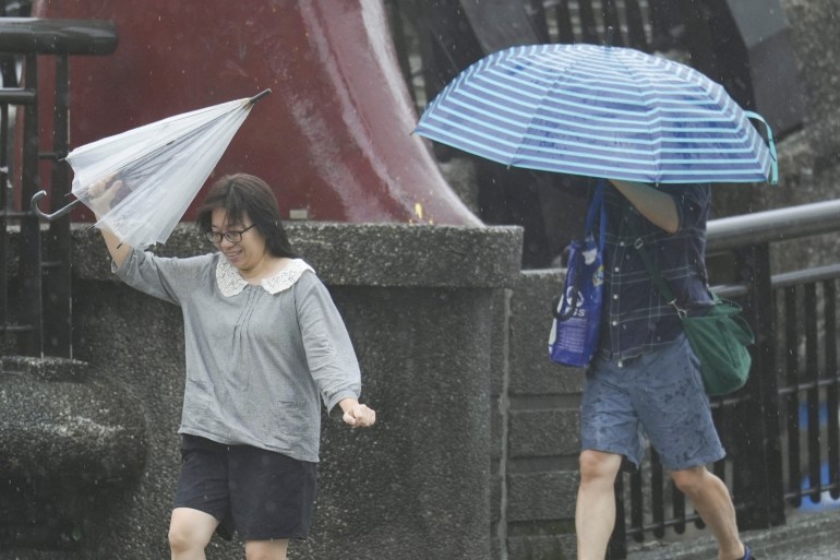 People hold umbrellas as Typhoon Kong-rey approaches in Keelung, Taiwan October 31, 2024. REUTERS/Walid Berrazeg