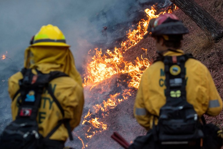 Firefighters watch as the Palisades Fire burns at the Mandeville Canyon, a neighbourhood of Los Angeles, California. [Ringo Chiu/Reuters]