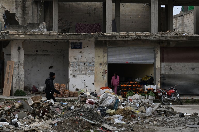 A man walks past a shop selling fruits and vegetables in a war-ravaged street in the town of Qusayr in Syria's central Homs province on February 12, 2025. (Photo by LOUAI BESHARA / AFP)