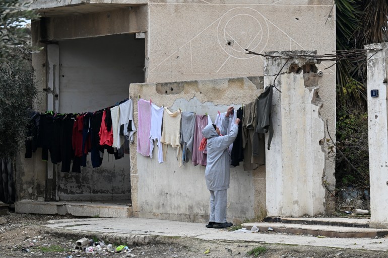 A woman hangs laundry to dry in a war-damaged neighbourhood in the town of Qusayr in Syria's central Homs province on February 12, 2025. (Photo by LOUAI BESHARA / AFP)