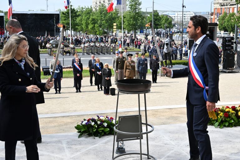 France's Delegate Minister to Memory and Veterans Affairs Patricia Miralles (L) and Reims mayor Arnaud Robinet light the flame of remembrance during the Commemoration of the 80th anniversary of the end of World War II in Europe, in Reims, north eastern France, where Nazi Germany signed its initial 1945 surrender, on May 7, 2025.