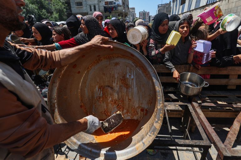 Palestinians queue for a portion of hot food distributed by a charity kitchen at the Nuseirat refugee camp in the central Gaza Strip on May 5, 2025.