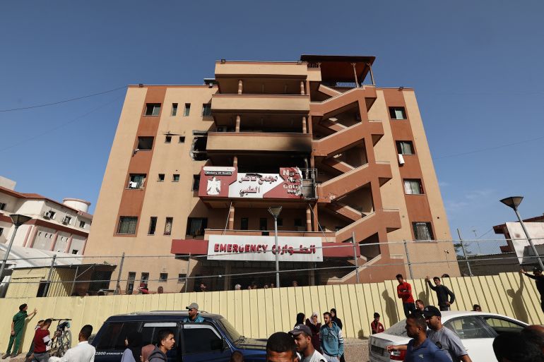 People and traffic pass the fence of the Nasser hospital in Khan Yunis which was hit in an Israeli strike at dawn that targeted the southern Gaza Strip city on May 13, 2025.