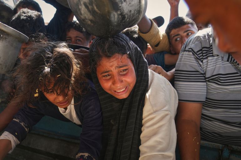 Palestinians struggle to obtain donated food at a community kitchen in Khan Younis, in the southern Gaza Strip, Friday, May 9, 2025. (AP Photo/Abdel Kareem Hana)