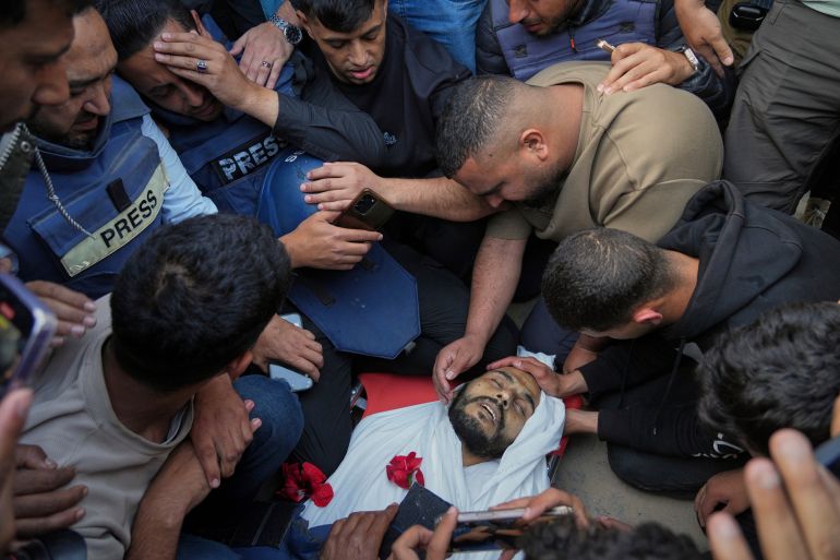Colleagues mourn over the body of Palestinian journalist Hassan Essliah during his funeral, after he was killed in an overnight Israeli army strike on Nasser Hospital in Khan Younis, Gaza Strip, Tuesday, May 13, 2025. (AP Photo/Jehad Alshrafi)